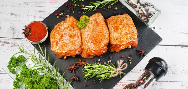 Three pieces of chicken thighs marinated in red sauce on a kitchen cutting board, on a light background, banner. Convenience food, quick cook, semi-cooked food.Top view.