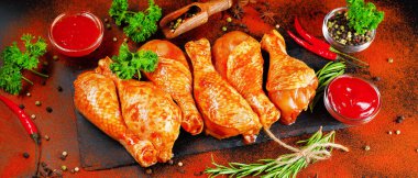 Siyah arka planda siyah bir yemek tahtasında taze biberiye yapraklarıyla marine edilmiş ızgara tavuk dolması. Yarı bitmiş ürün, marine edilmiş ürün, yemek pişirme. Baharatlı et pankartı..