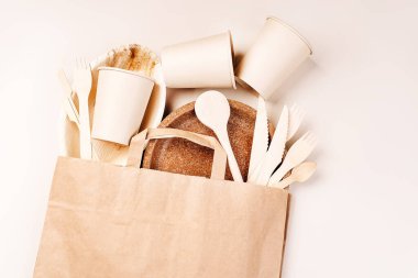 Eko-el yapımı kağıt sofra takımı, fincanlar, fast food kapları. Geri dönüşüm, çevre dostu konsept. Atılabilir eko çatal bıçak takımı, tabaklar, kaşıklar, bıçaklar, çatallar hafif bir arka planda. Yiyecek teslimatı için kağıt torba..