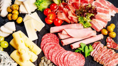 Charcuterie, İtalyan salamı, peynir, camembert ve domatesli zeytin karışımlı antipasti tabağı. Et aperatifi. Üst manzara. Antipasto tabağı. Peynirli soğuk et tabağı..