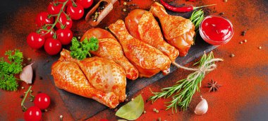 Biberiye yaprakları, taze kiraz domatesleri ve çeşitli baharatlarla birlikte, siyah bir yemek tahtasında marine edilmiş ızgara tavuk çorbası. Yakın plan, yarı bitmiş ürün, marine edilmiş ürün, hızlı pişirme..