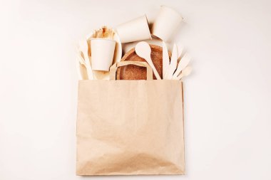 Tek kullanımlık sofra takımı, tabaklar, kaşıklar, bıçaklar, arka planda çatallar. Yiyecek teslimatı için kağıt torba. Anlaşıldı. Eko el yapımı kağıt sofra takımı, fincanlar, fast food kapları. Geri dönüşüm, çevre dostu konsept..