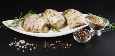 Baharatlı tavuk budu, sarımsak. Çiğ tavuk budu. Bitki sosuyla marine edilmiş, koyu bir zemin üzerinde taze biberiye, baharat..