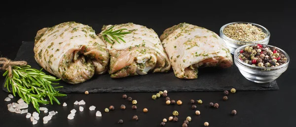 Raw Meat Chicken.Raw chicken thighs marinated in herbal sauce on a dark background with fresh rosemary, spices. Chicken thighs with spices, garlic.