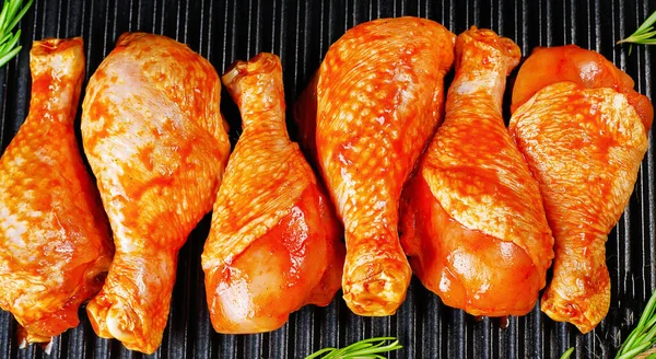 Barbecue marinated chicken dramstick on a black culinary board on a black background close-up. Semi-finished product, Marinated product, fast cooking. — Stock Photo, Image