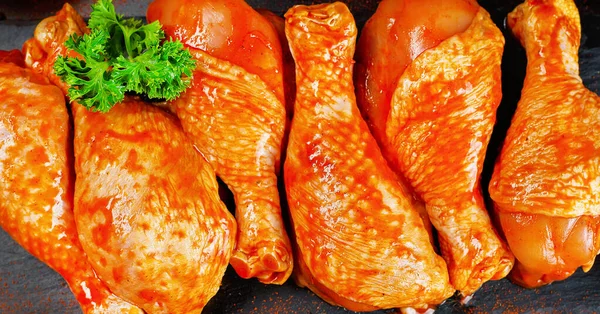 Convenience food, precooked.Raw Marinated chicken meat legs with spices for cooking for BBQ dark background. Top view.