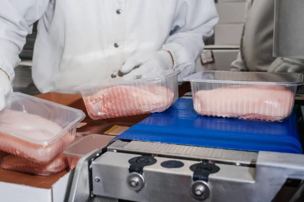 Línea para la producción de productos cárnicos semiacabados.Procesamiento de carne en la industria alimentaria.Embalaje de lonchas de carne en cajas en una cinta transportadora.planta moderna de procesamiento de aves de corral. — Foto de Stock