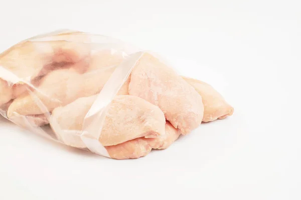 Zamrożone kawałki filetu z kurczaka na izolowanym białym tle.Kurczak świeże mięso w przezroczystej torbie. — Zdjęcie stockowe