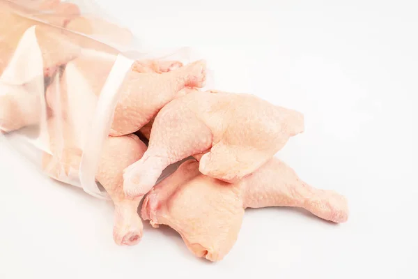 Trozos congelados de pata de pollo sobre un fondo blanco aislado.Carne fresca de pollo en una bolsa transparente. — Foto de Stock