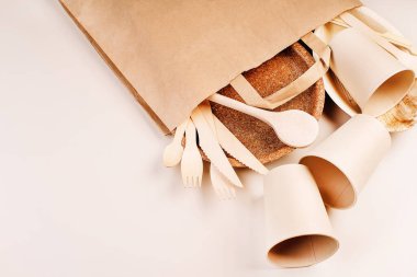 Eko-el yapımı kağıt sofra takımı, fincanlar, fast food kapları. Geri dönüşüm, çevre dostu konsept. Atılabilir eko çatal bıçak takımı, tabaklar, kaşıklar, bıçaklar, çatallar hafif bir arka planda. Yiyecek teslimatı için kağıt torba..