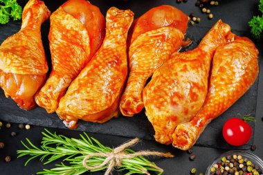 Siyah bir arka planda siyah bir mutfak tahtasının üzerinde salamura edilmiş tavuk dramstick 'i. Yarı bitmiş ürün, marine edilmiş ürün, hızlı pişirme..