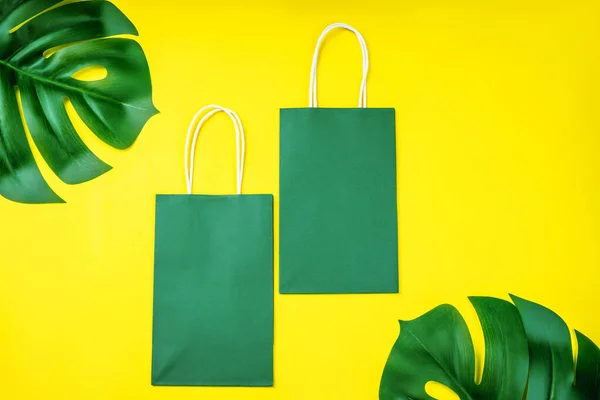 Eco-friendly paper bags on yellow background.Recycled paper shopping bag with green leaves .Set of multiple disposable paper bags for takeaway food, gifts,and mock up.
