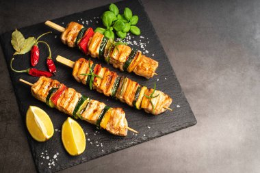 .Kabaklı tavuk şiş kebap. Manzaralı. Siyah arka planda sebzeli ızgara tavuk kebabı. Şişte ızgara tavuk eti..