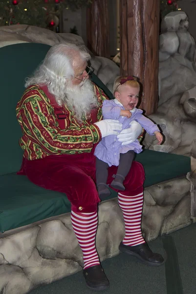 Jultomte med gråtande barn girl. Stockbild