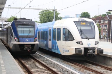 Hollanda 'daki Zwolle İstasyonu platformu boyunca NS ve Arrica Stadler' in mavi yerel banliyö treni