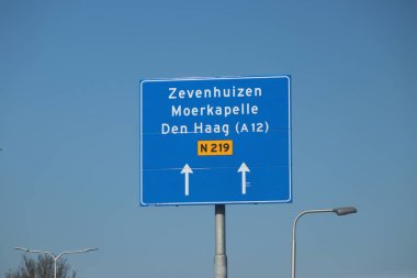 Hollanda 'daki Nieuwerkerk aan den IJssel' deki N219 yolunun mavi yönü ve bilgi işareti