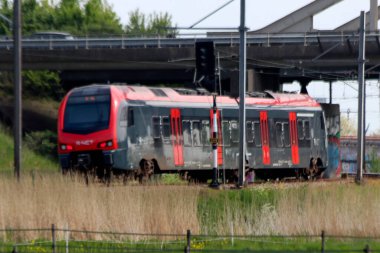 Red and black train vehicle of R-Net heading to Gouda from Alphen  in the Netherlands