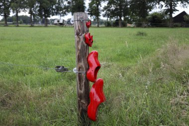 Hollanda Oldebroek 'te yürüyüş güzergahında çitlerdeki kırmızı takunyalar.