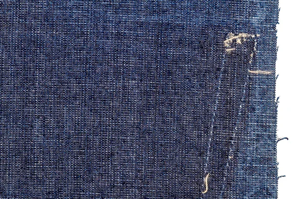 Piece of blue jeans fabric with a ripped of back pocket isolated on white background. Rough uneven edges. Denim fabric torn.