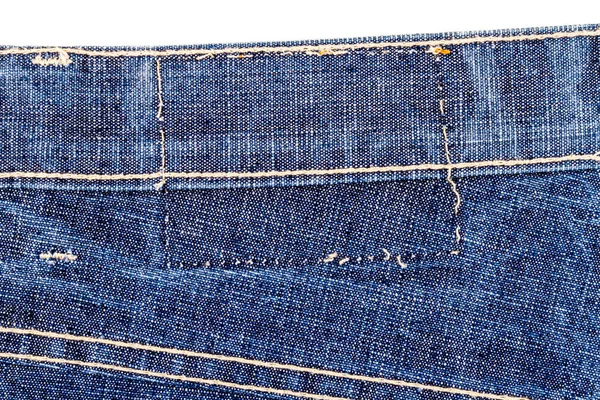 Piece of blue jeans fabric with a ripped of label isolated on white background. Rough uneven edges. Denim fabric torn.