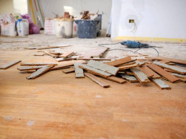 Parquet floor in wood glued to the slab, removed with an electric hammer in an apartment under renovation. In the foreground the strips of parquet removed and in the background the work tools. clipart