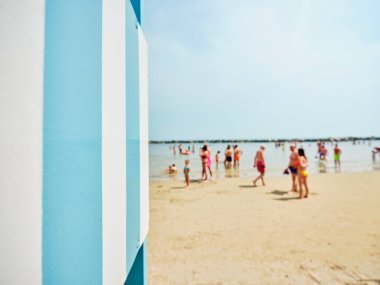 Ön planda cankurtaran kulesi, arka planda güneşli bir yaz gününde Adriyatik Denizi kıyısında serinleyen bazı yüzücüler, İtalya.