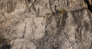 Rock wall of volcanic origin with shades of red, orange. Cliff overlooking the sea, in the Gulf of Policastro in Cilento, Italy.