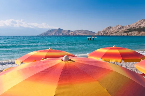 Orange parasoller på stranden i Baska - Krk - Kroatien - Stock-foto