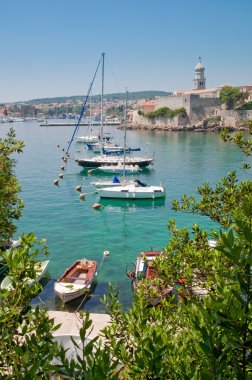 Boats on little port beside Krk old town view with vegetation - clipart