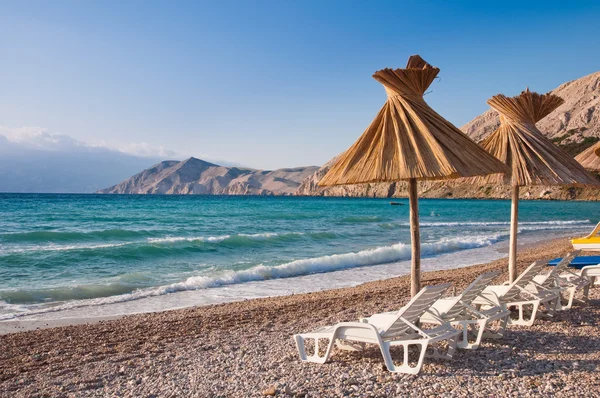 Sunshade and deck chair on beach at Baska in Krk - Croatia — Stock Photo, Image