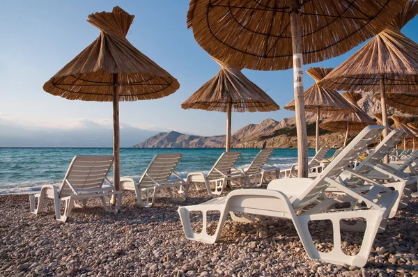 Chaises longues et parasol sur la plage à Baska - Krk - Croatie — Photo