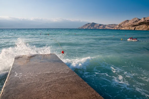 La vague se brise sur la jetée sur la plage à Baska - Krk - Croatie — Photo