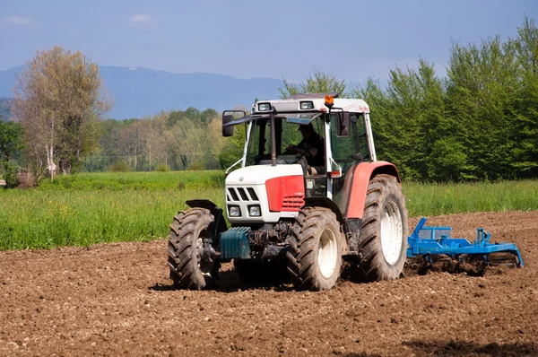 Roter und weißer Traktor mit Rüttelfeldern vorne — Stockfoto