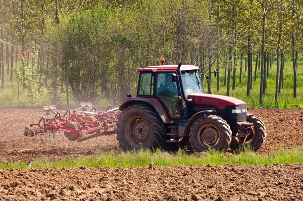 Červený traktor s vibrocultor na boční pohled na pole — Stock fotografie