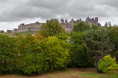Carcassonne fırtınalı gökyüzü ile ağaçların arkasında'deki eski müstahkem şehir