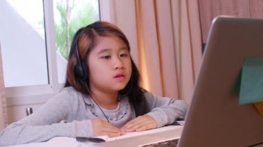 Ev konseptinden 4K öğren. Asyalı kız öğrenciler covid-19 salgınından dolayı internetten sanal internet dersleri alıyorlar. Kız öğrenci evde tabletle online öğrenim görüyor
