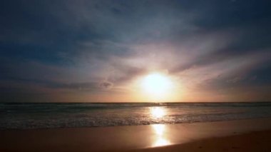 4K Günbatımı gökyüzü ile güzel tropikal plaj. Güzel Phuket plajı, Andaman Denizi yaz konseptinde ünlü bir turizm merkezidir. Denizin üzerinde günbatımı olan gerçek bir drone manzaralı tropikal plaj