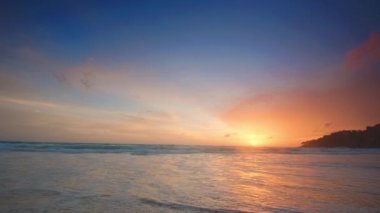 4K Günbatımı gökyüzü ile güzel tropikal plaj. Güzel Phuket plajı, Andaman Denizi yaz konseptinde ünlü bir turizm merkezidir. Denizin üzerinde günbatımı olan gerçek bir drone manzaralı tropikal plaj