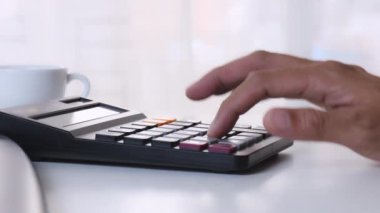 4K adam ofis masasında hesap makinesi kullanıyor. Erkek el çabukluğu hesap makinesi. İş adamı eli ofiste hesap makinesi kullanıyor. Ahşap masada aile bütçesi hesaplaması.