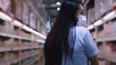 Yeni normal sosyal mesafeli konsept Asyalı kadın koruyucu yüz maskesi takıyor ve marketten meyve seçiyor. Coronavirüs sonrası markette meyve satan kadınlar, covid-19 salgını