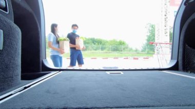 4K erkek ve kadın bir çift, alışveriş arabasında, meyve ve sebzelerle dolu alışveriş çantasıyla ve arabada kağıt poşetlerle birlikte yürüyorlar. İçeriden çekilmiş Aile yaşam tarzı konsepti