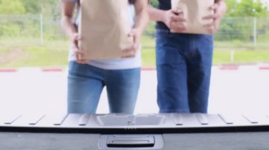 4K erkek ve kadın bir çift, alışveriş arabasında, meyve ve sebzelerle dolu alışveriş çantasıyla ve arabada kağıt poşetlerle birlikte yürüyorlar. İçeriden çekilmiş Aile yaşam tarzı konsepti