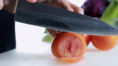 4K Kadın Eli Kesme Kurulu 'nda taze domates kesiyor. Dişi el, çiğ domatesi kesme tahtasındaki bıçakla daireler çiziyor. sağlıklı gıda konsepti.