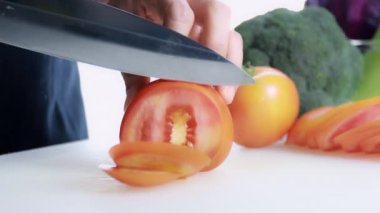 4K Kadın Eli Kesme Kurulu 'nda taze domates kesiyor. Dişi el, çiğ domatesi kesme tahtasındaki bıçakla daireler çiziyor. sağlıklı gıda konsepti.