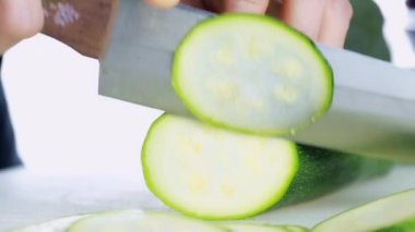 4K Kadın Eli Kesme Kurulu 'nda taze kabak kesiyor. Kadın eli, çiğ Japon salatalığını kesme tahtasındaki bıçakla daireler çiziyor. sağlıklı gıda konsepti.