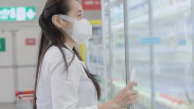 Koruyucu maskeler takan Asyalı kadınlar süpermarketlerde alışveriş arabasını itip tutuyor. Kadın, yiyecek bir şeyler almak için bakkal arıyor. Covid-19 'dan sonra yeni normal. Aile kavramı.