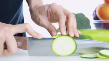 4K Kadın Eli Kesme Kurulu 'nda taze kabak kesiyor. Kadın eli, çiğ Japon salatalığını kesme tahtasındaki bıçakla daireler çiziyor. sağlıklı gıda konsepti.