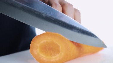 4K Kadın Eli kesme tahtasında taze havuç kesiyor. Dişi el çiğ havuçları kesme tahtasındaki bıçakla daireler halinde dilimliyor. sağlıklı gıda konsepti.