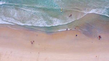 4K Aerial insansız hava aracı, Phuket, Tayland 'da günbatımı olan tropikal plajdaki insanların en iyi görüntüsü Andaman Denizi' nde ünlü bir turizm merkezidir. Sahilde oynayan mutlu insanlar.