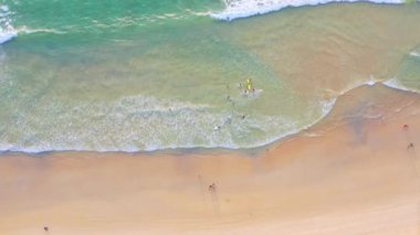 4K Aerial insansız hava aracı, Phuket, Tayland 'da günbatımı olan tropikal plajdaki insanların en iyi görüntüsü Andaman Denizi' nde ünlü bir turizm merkezidir. Sahilde oynayan mutlu insanlar.